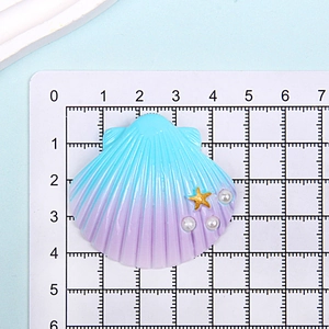 Macro detail of purple shell resin accessory with starfish and pearls on a grid