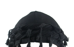 Detail of black turban with satin lining and long twisted tassel on white background