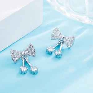 Detail of silver bow earrings with sparkling crystals and hanging round stone tassels