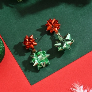 Detail of festive Christmas red and green bow-knot drop earrings on a holiday backdrop