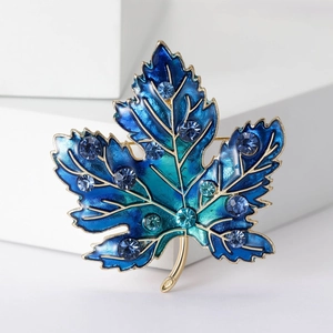 Detailed close-up of maple leaf brooch with blue crystal inlay and gold-tone finish