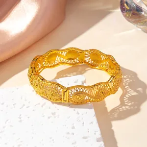Detail of vintage gold hollow carved bangle with intricate spiral patterns on stone base