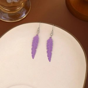 Close-up of purple feather-shaped dangle earrings with silver hooks on ceramic