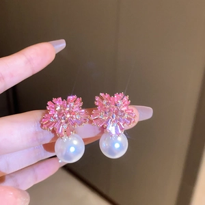 Detailed view of pink zircon flower stud earrings with a large white hanging pearl