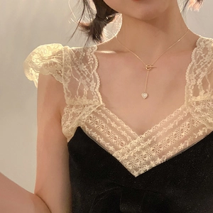 Detailed view of a gold heart pendant necklace with OT toggle clasp on a female model