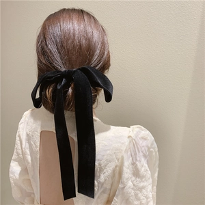 Elegant black velvet bow hair tie with long ribbons on brunette model's ponytail