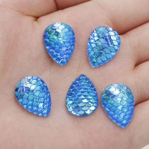 Macro view of blue teardrop resin rhinestones with fish scale texture on palm