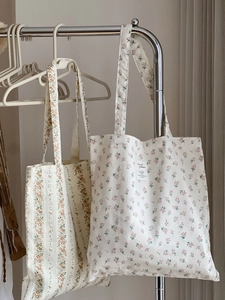 Detailed view of floral cotton canvas tote bags hanging in a minimalist interior setting