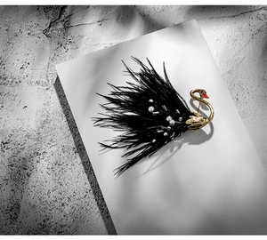 Detail of elegant black swan brooch with soft feathers, white pearls and shiny rhinestones