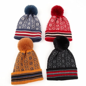 Flat lay of four winter knit beanies with geometric patterns and fluffy pom-poms