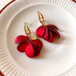 Elegant red flower drop earrings with golden frames and sparkling crystals in a ceramic dish