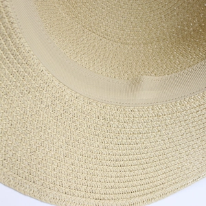 Macro detail of natural straw sun hat showing tight spiral weave and interior sweatband