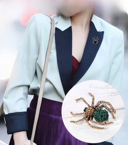 Detail of spider brooch featuring emerald and amber rhinestones on a vintage alloy body