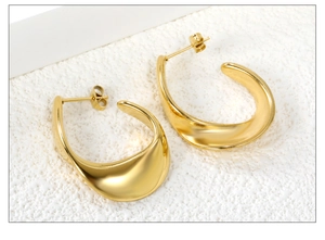 Close-up of golden C-shaped hoop earrings with mirror finish and curved minimalist design