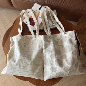 Minimalist cream cotton linen tote bags with jacquard textures on a wooden table