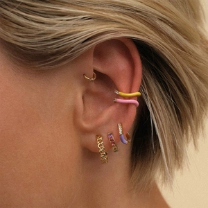 Close-up of gold ear cuffs with colorful enamel and zircon stones worn on model's ear