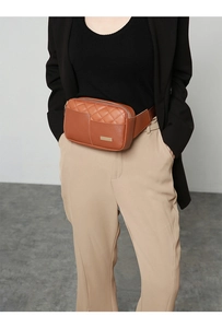 Close-up of brown PU leather chest bag with quilted embroidery and metal nameplate