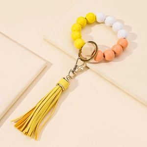 Beaded tassel wristlet keychain with yellow, white and peach beads on geometric background