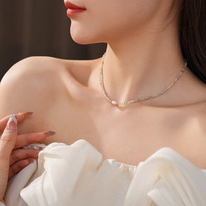 Detailed view of beaded titanium steel necklace with grey stones and white pearl on neck
