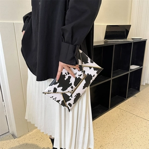 Minimalist black and white cow print envelope clutch bag with gold metallic trim accents