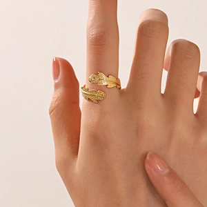 Golden feather shaped open adjustable stainless steel ring shown on a finger
