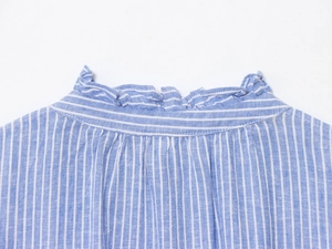 Détail de chemise en coton à rayures bleues montrant le col montant volanté et la texture