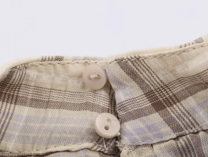 Détail macro du tissu à carreaux et boutons beiges mats sur un haut court pour femme