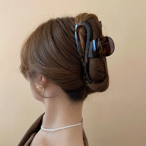 Detail of a large leopard print hair claw clip worn on hair with a sleek hollow structure