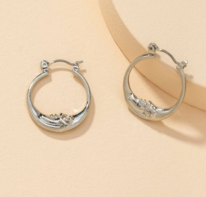 Detail of silver hoop earrings featuring an intricate crescent moon face relief design
