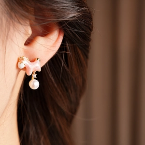 Close-up of pink puppy pearl earring with 18K gold plating on a model's ear