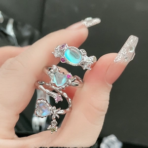 Macro detail of three silver rings with heart-shaped moonstones and colorful crystals