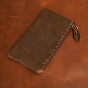 Detail view of brown crazy horse leather wallet with vintage texture and metal zipper