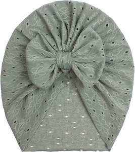 Detailed texture of baby beanie with hollow knit patterns and large bow in sage green
