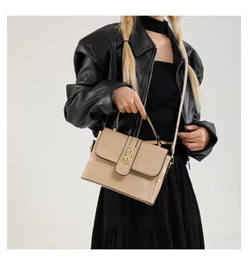 Chic beige crossbody bag with gold round lock worn by model in black leather jacket