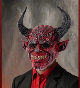 Close-up of red demon mask with black horns, pointed ears and detailed skin texture
