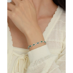 Macro shot of silver bracelet with emerald teardrop stones on woman's wrist