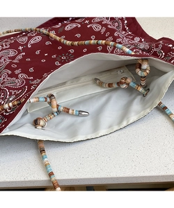 Detail of burgundy paisley tote bag showing white lining and internal zipper pocket