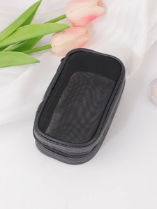 Detail of a portable black mesh cosmetic bag with a secure zipper on a white surface