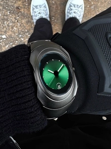Wrist shot of Y2K irregular quartz watch with grey metal case and green sunray dial