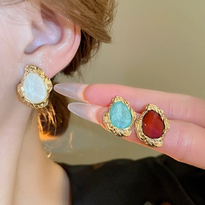 Macro detail of vintage geometric stud earrings with gold texture and color inlay