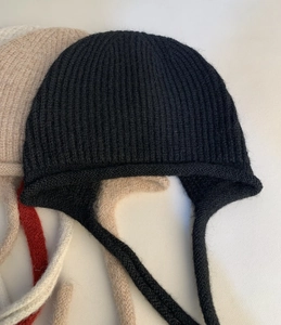 Dettaglio di cappelli in maglia di lana con paraorecchie e lacci lunghi colorati