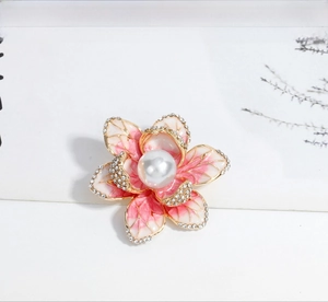 Detail of enamel flower brooch with rhinestones and a white pearl center on petals