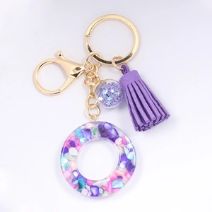 Detail of resin alphabet keychain with purple tassel and colorful crushed stone filling