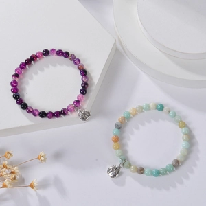 6mm Purple Agate and Zebra Stone bead bracelets with ladybug charms on white pedestals