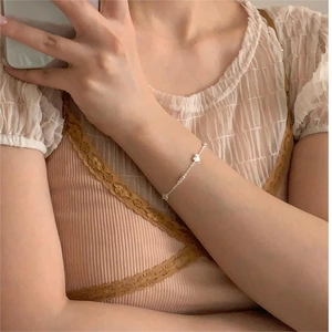 Close-up of S925 sterling silver heart charm bracelet worn by a model in soft light
