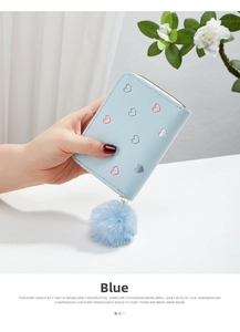 Detail of light blue women's short wallet with heart embroidery and fluffy ball charm