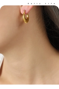 Close-up of gold-plated U-shaped earrings with intricate wheat ear pattern engraving