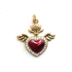 Detailed view of a golden sacred heart pendant with red enamel and small zircon stones