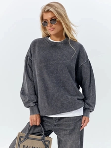 Detail of oversized washed black sweatshirt showing vintage cotton texture and ribbed cuffs