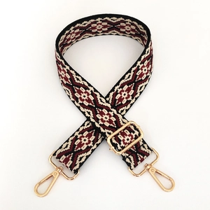 Detail of burgundy geometric jacquard woven bag strap with gold metal lobster clasps